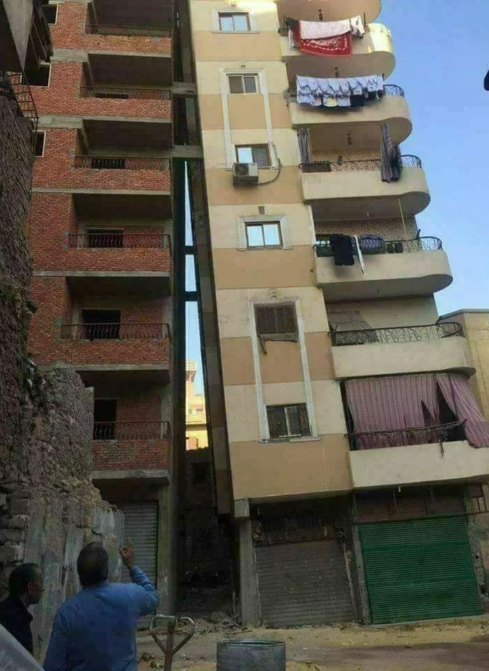Leaning building with balconies close to a brick structure, illustrating an architecture fail.