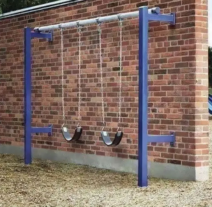 Swings facing a brick wall highlight an architecture fail with poor design choices.
