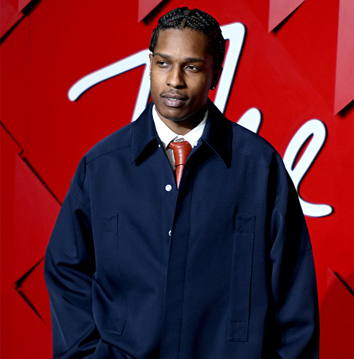 Young man in a navy coat and red tie at an event, amid Met Gala dress code controversy. Young man in a navy coat and red tie at an event, amid Met Gala dress code controversy.