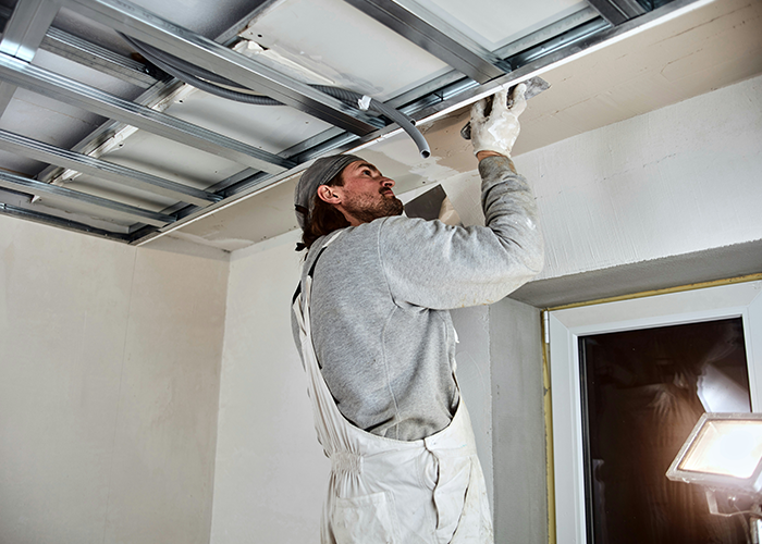 Person restoring a cabin ceiling, wearing work clothes and using a trowel, with a focus on renovation and repair efforts. Person restoring a cabin ceiling, wearing work clothes and using a trowel, with a focus on renovation and repair efforts.