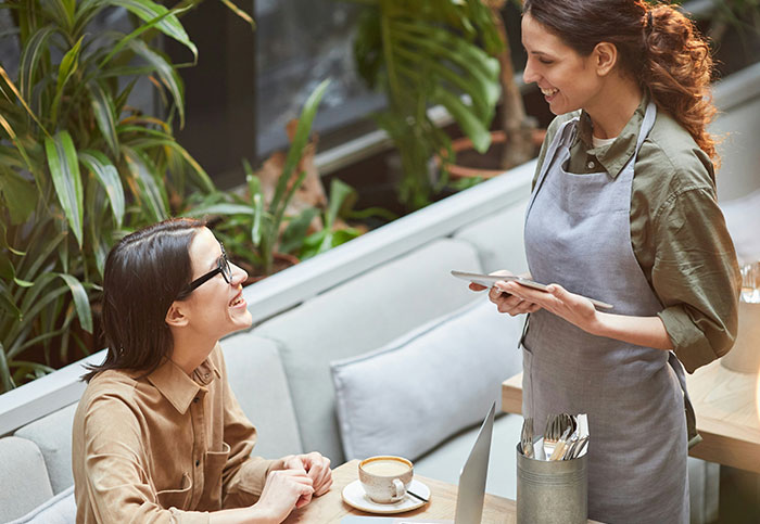 Server discussing tipping with a customer in a cafe, sparking a debate on tipping customs.