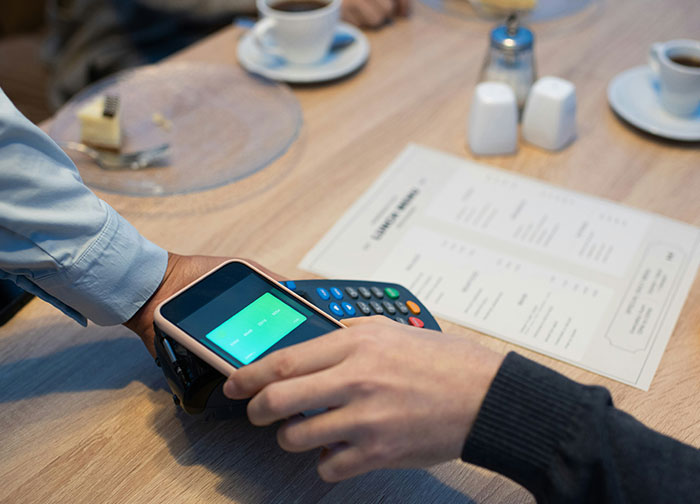 Customer using a phone to pay at a restaurant, sparking a debate on tipping practices.