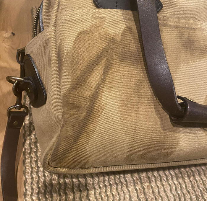 Close-up of a partially visible leather bag on a textured surface.