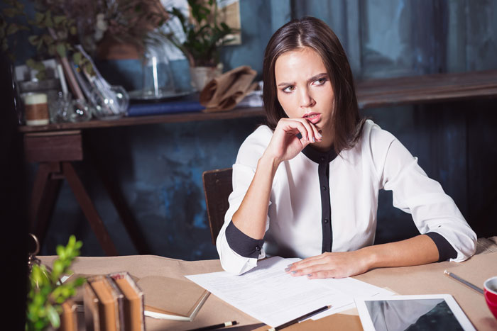 Woman in a white blouse sitting at a table, looking concerned, papers scattered, with a tablet nearby; child-free wedding theme. Woman in a white blouse sitting at a table, looking concerned, papers scattered, with a tablet nearby; child-free wedding theme.