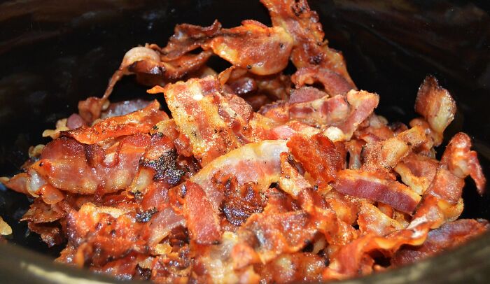 Crispy cooked bacon slices in a bowl, related to unpopular opinion poll discussion.