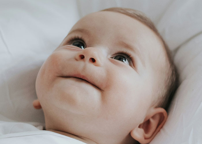 Smiling baby looking up, representing baby names in focus.