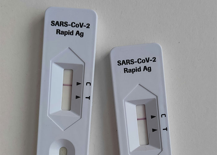 SARS-CoV-2 Rapid Antigen tests with visible result lines on a white surface.