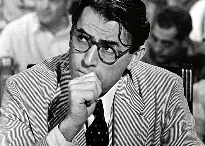 A pensive man in glasses and a suit, contemplating a baby name.