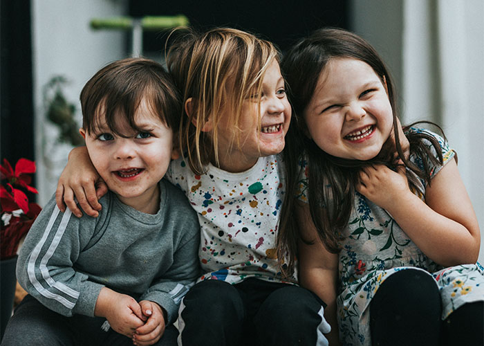 Children laughing together, wearing colorful clothing, illustrating a happy moment related to baby name discussions.