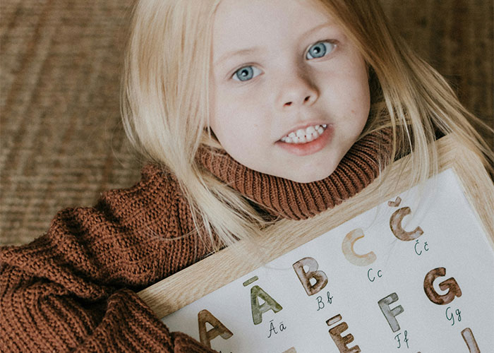 Child holding alphabet chart, relevant to baby names discussion.