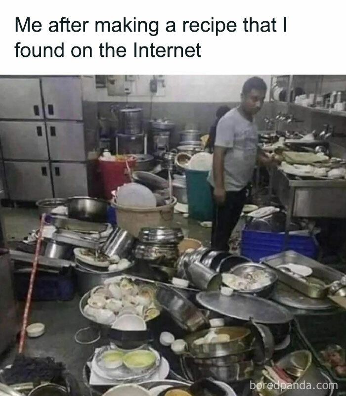 Man standing in a messy kitchen with dishes piled everywhere, humorously representing barely functioning.