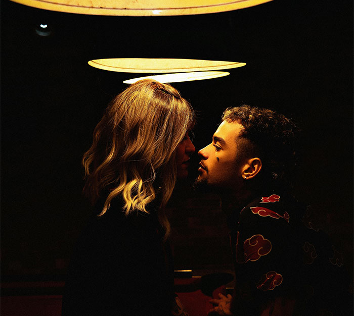 A couple leans in for a kiss under dim bar lights, capturing unforgettable bartender moments.