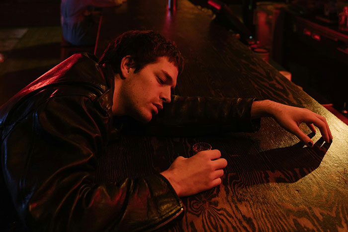 Person in a bar with a drink, looking reflective. Bartender memory moment captured in a dimly lit setting.