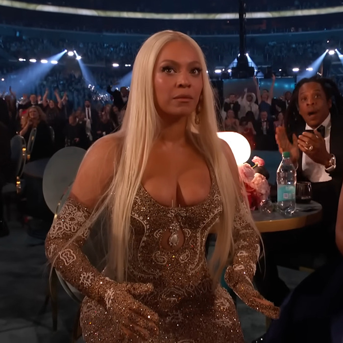 Beyonc&eacute; experiencing a wardrobe malfunction at the Grammys, wearing a shimmering gold dress.