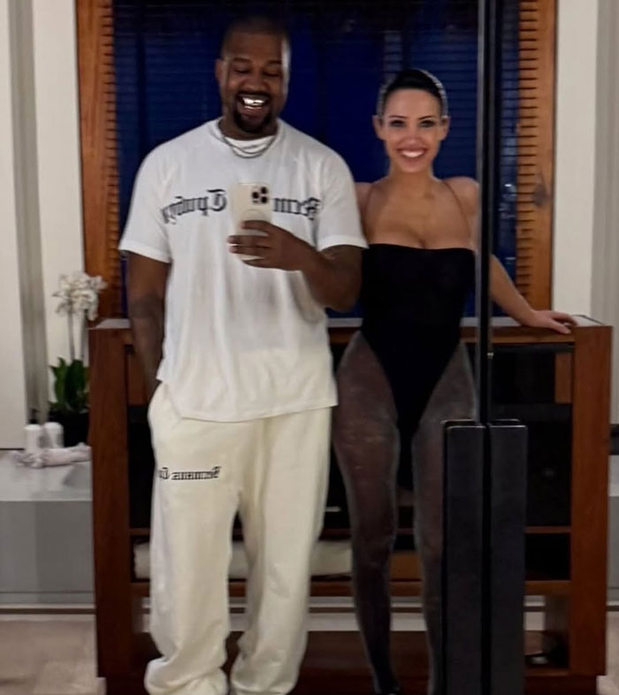 Kanye West and Bianca Censori pose in a mirror selfie, wearing casual and stylish attire.