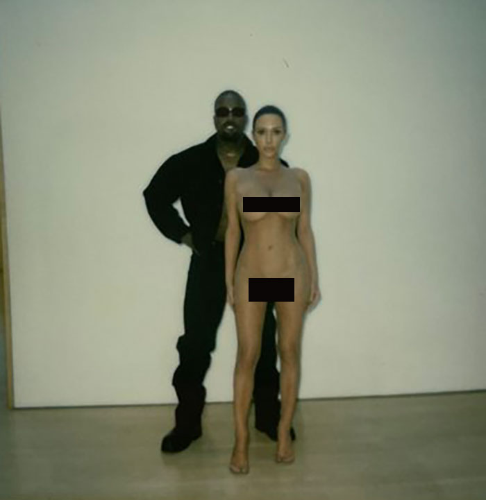 Man in black outfit and woman standing in front of white background; related to Bianca Censori and Kanye topic.