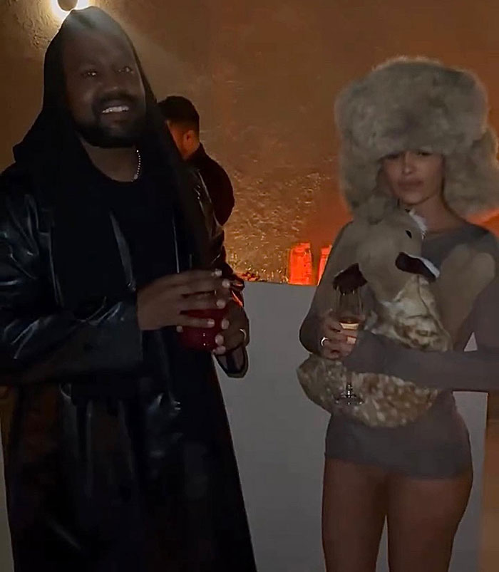 Man and woman at a dim-lit event, holding drinks, with the main SEO keyword: Kanye West and Bianca Censori.