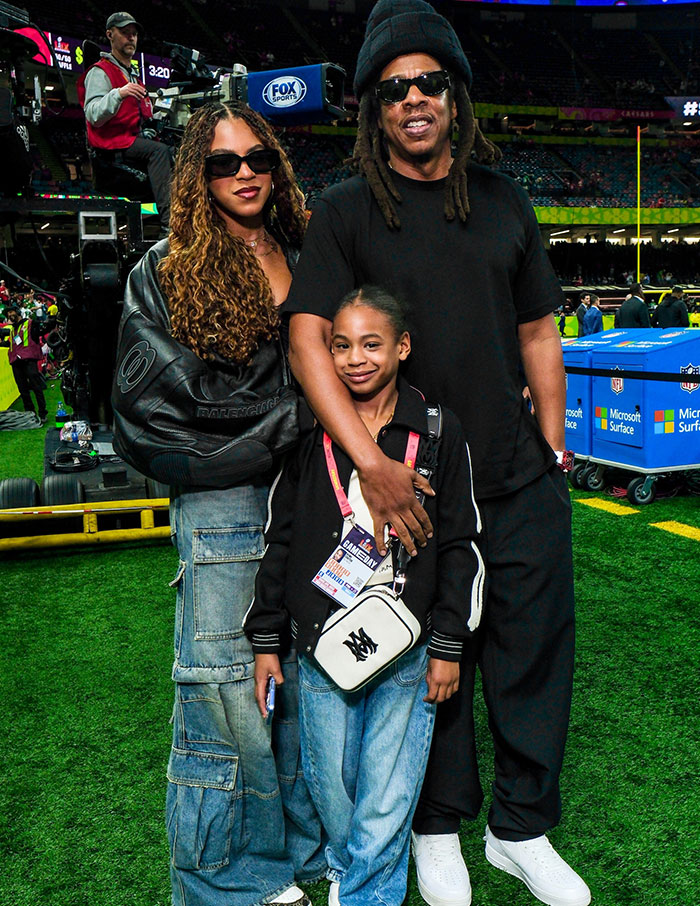 A family posing on the field in stylish attire at Super Bowl 2025, capturing one of the head-turning looks of the event.