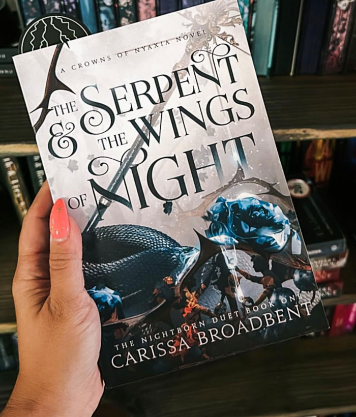 Hand holding "The Serpent and the Wings of Night" book, a recommendation for fans of 'Onyx Storm'.