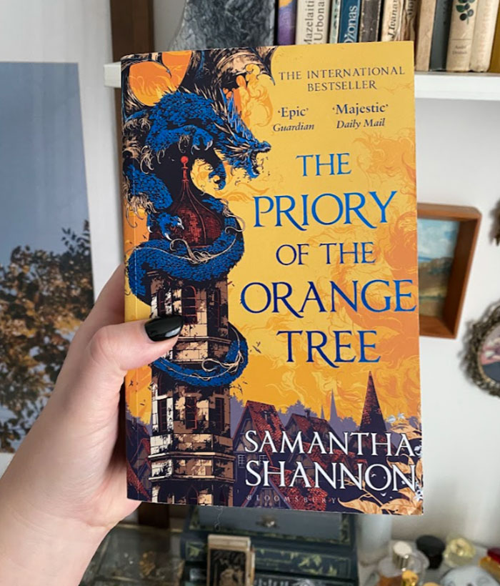A hand holding "The Priory of the Orange Tree" by Samantha Shannon, an ideal next read after "Onyx Storm."