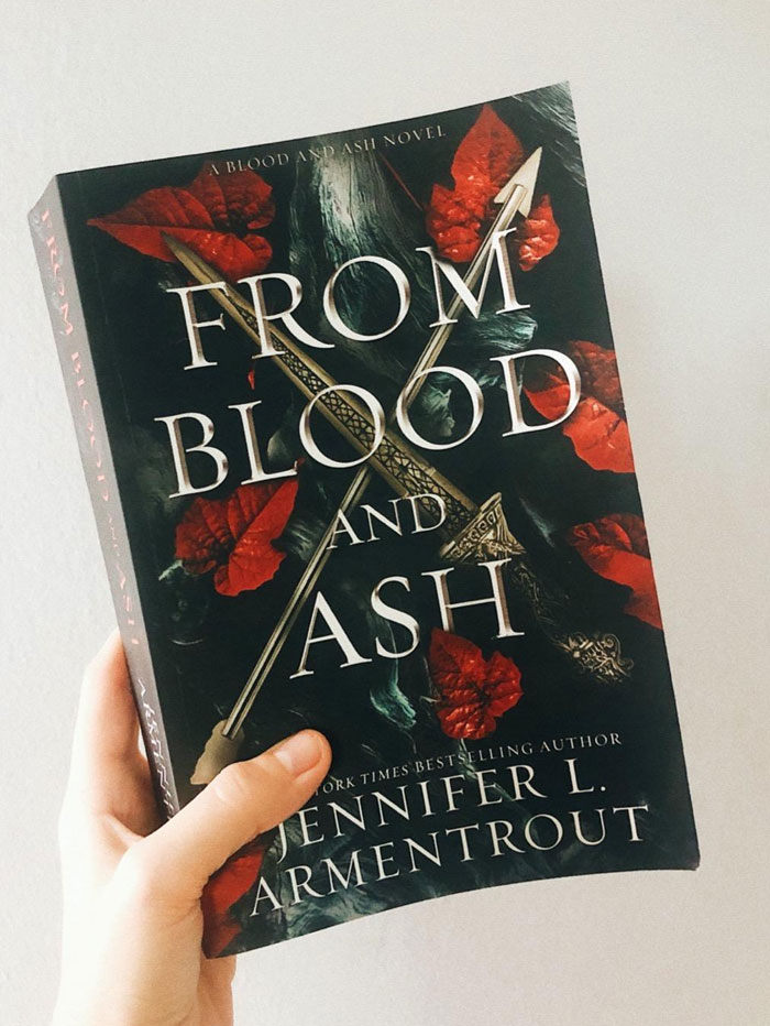 "From Blood and Ash book held in hand with dark floral cover, an option after binge-reading Onyx Storm by Rebecca Yarros."
