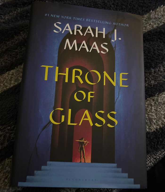 "Cover of the book 'Throne of Glass' by Sarah J. Maas on a textured surface."