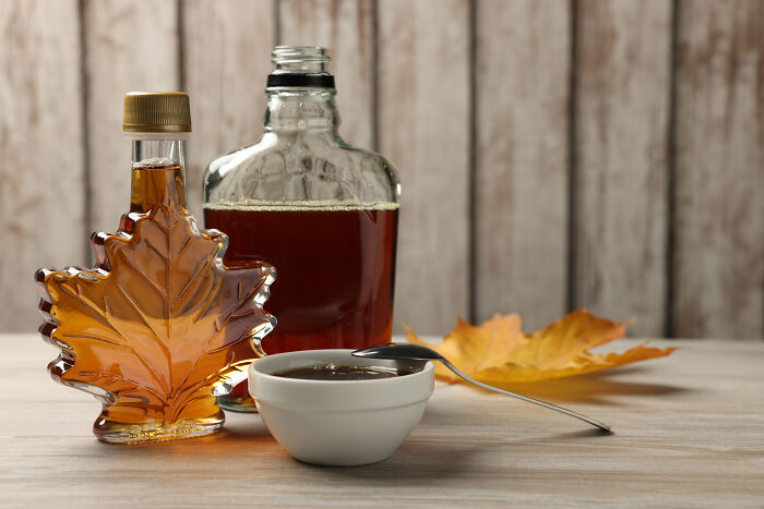 Maple syrup bottles and dish with spoon, symbolizing goods to buy before tariff price hikes.