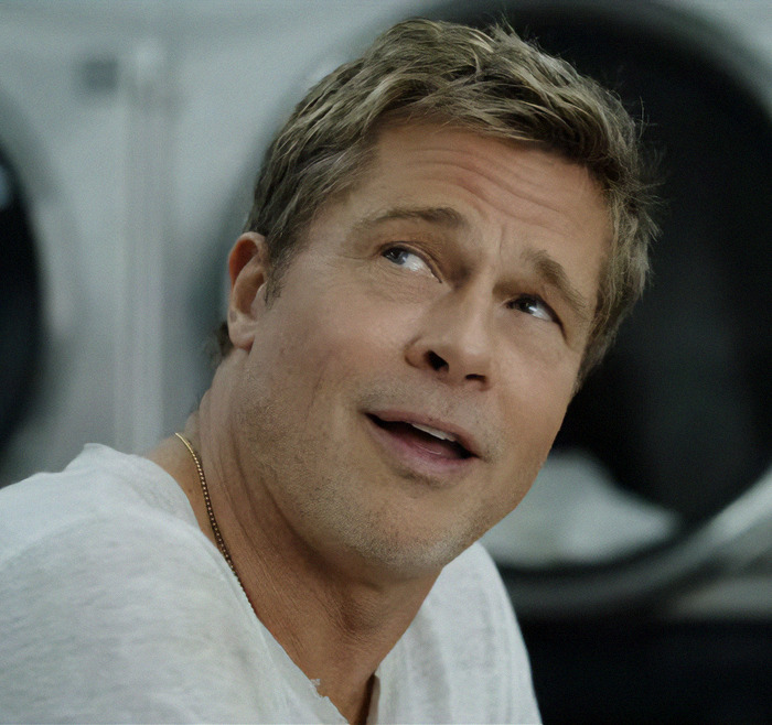 A man in a white shirt smiling, highlighting tattoos honoring someone special.