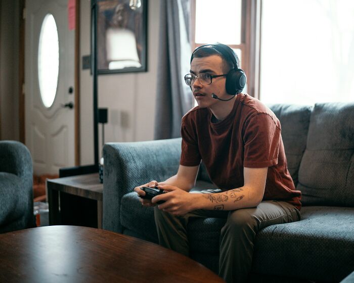 Person wearing headset, sitting on a couch while gaming, symbolizing professions that might become useless soon.