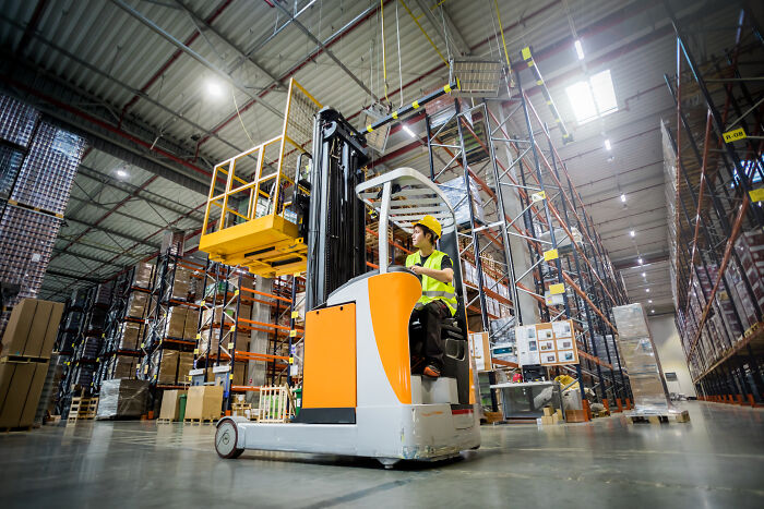 Worker operating forklift in a large warehouse, capturing one of the insane workplace moments in industrial settings.