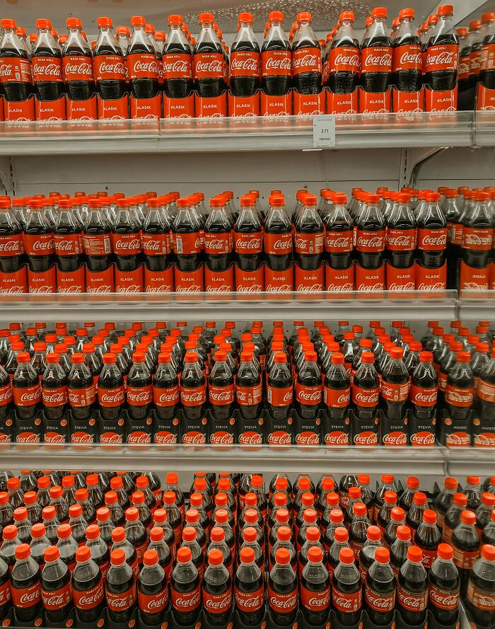 Workplace scene with shelves packed full of Coca-Cola bottles in a store setting.