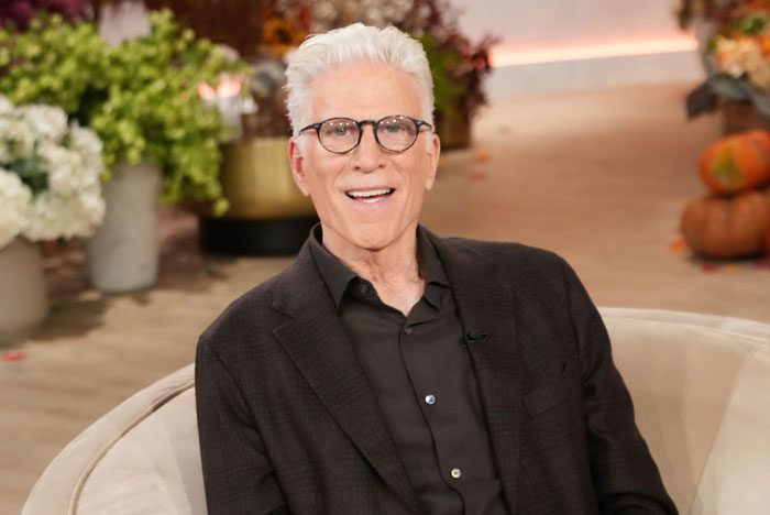 Ted Danson smiling in a dark suit, seated indoors with flowers in the background, related to "A Man On The Inside" cast.