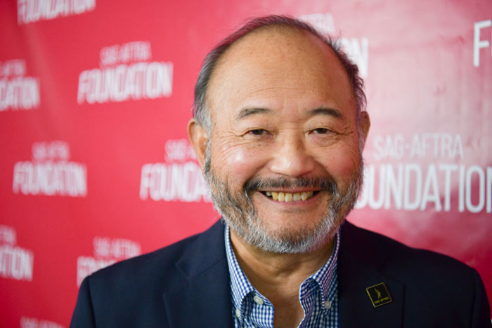 Smiling Clyde Kusatsu at SAG-AFTRA event, wearing a suit, related to Netflix series cast "A Man On The Inside".