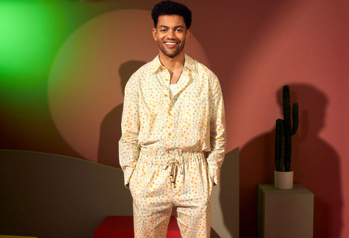 Miles Fowler from A Man On The Inside cast in patterned outfit, standing indoors with a colorful backdrop.