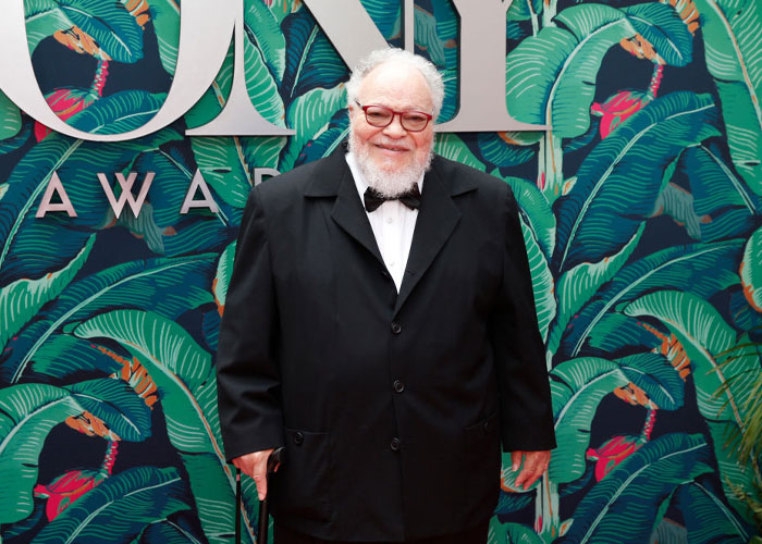 Stephen McKinley, a cast member of "A Man On The Inside" in a formal suit, posing at a vibrant event backdrop.