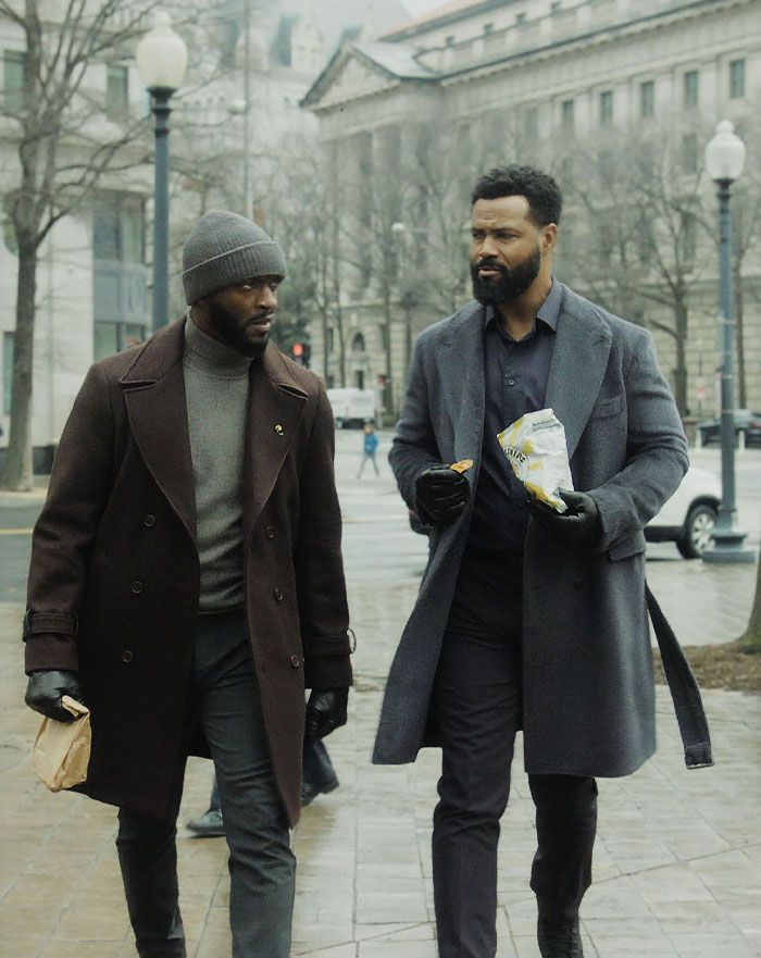 Aldis Hodge and Isaiah Mustafa in winter coats walking outdoors, discussing. Scene from Amazon's new Alex Cross thriller show.