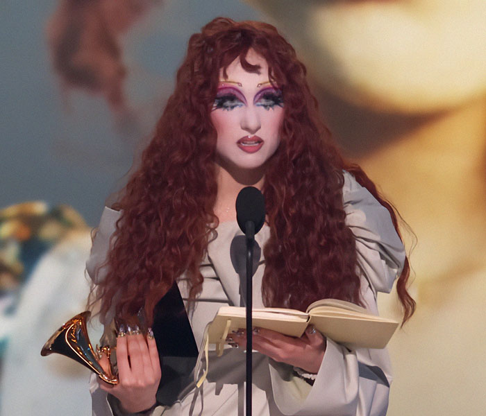 Person with dramatic makeup holding a Grammy award and book at the 2025 Grammy Awards.