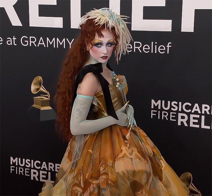 Chappell Roan at a Grammy event wearing a colorful dress, posing in front of a backdrop with music symbols. Chappell Roan at a Grammy event wearing a colorful dress, posing in front of a backdrop with music symbols.