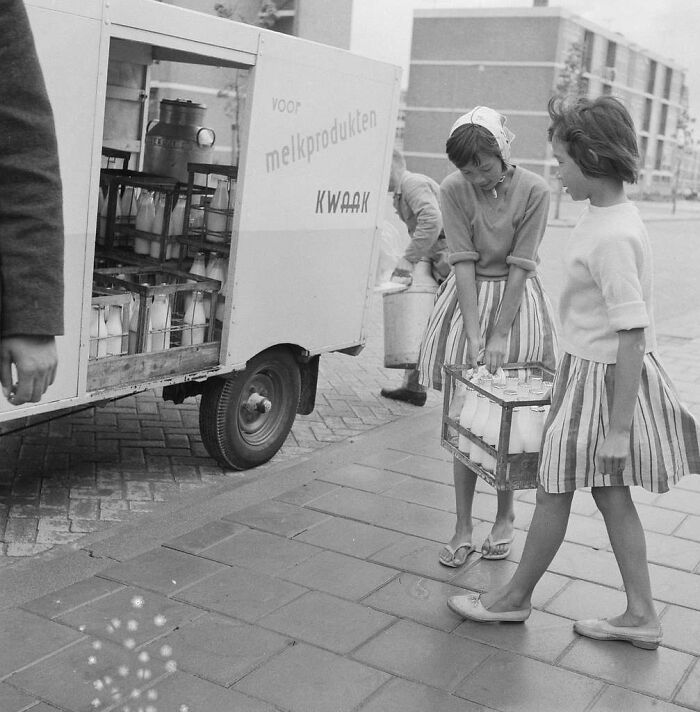 Milk delivery van with people carrying crates, illustrating jobs that died out as society evolved.