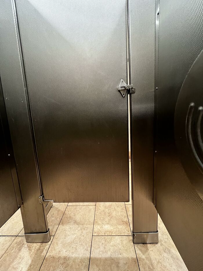 Public restroom stall with metallic door slightly ajar, showing typical USA architecture that confuses some foreigners.