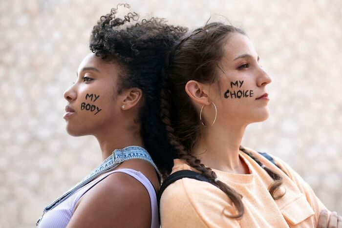Two women standing back-to-back with "My Body" and "My Choice" written on their faces; concept of personal freedoms.