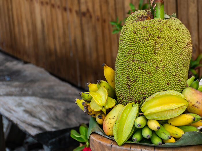Exotic fruits including jackfruit and starfruit displayed on a rustic wooden table.