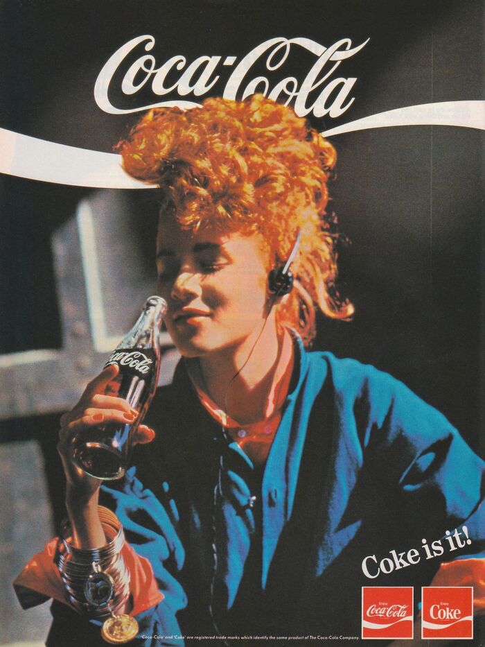Young woman with curly hair enjoying a Coca-Cola bottle, embodying vintage-commercials style. "Coke is it" slogan displayed.