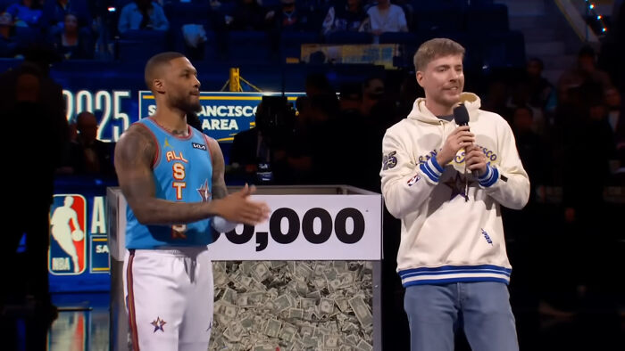 College student with NBA star Dame Lillard, holding microphone, celebrating a $100K win at shooting challenge event. College student with NBA star Dame Lillard, holding microphone, celebrating a $100K win at shooting challenge event.