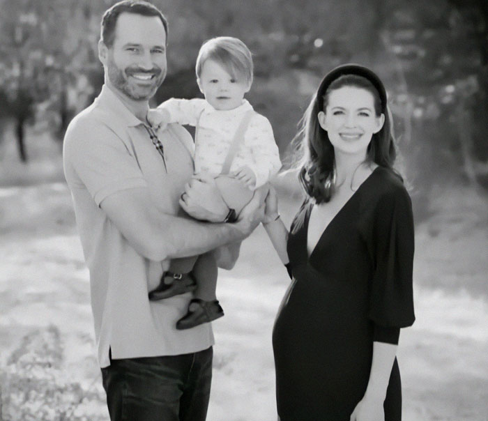 Family smiles outdoors; parents joyfully hold toddler after autism treatment success.