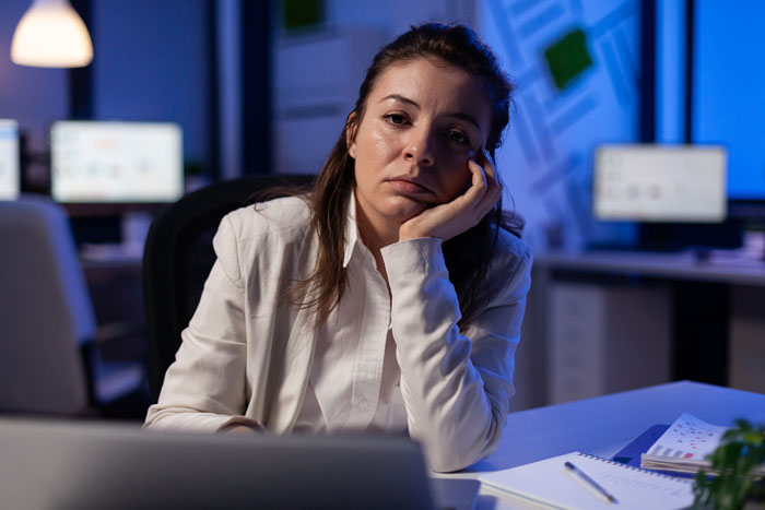 Woman in an office looking at a laptop, appearing thoughtful. Woman in an office looking at a laptop, appearing thoughtful.