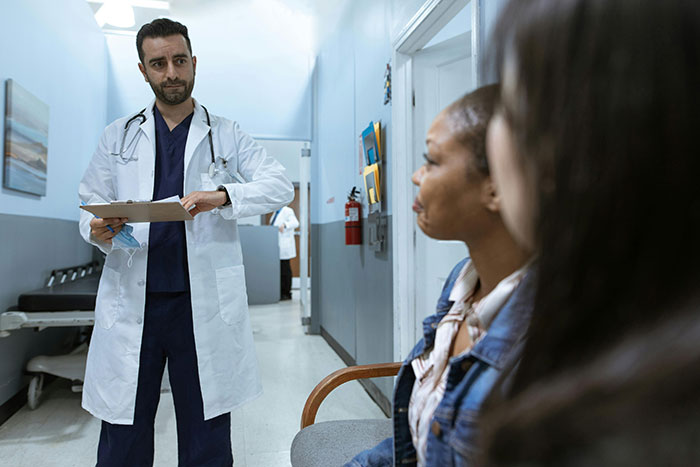 Doctor discussing results with two patients in a hospital hallway. Doctor discussing results with two patients in a hospital hallway.