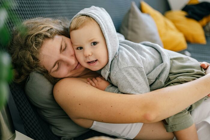 A child in a gray hoodie cuddling with a woman on a sofa, representing creepy things kids say themes.