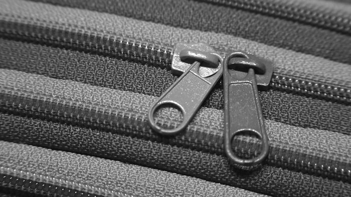 Close-up of dual zippers on fabric, suggesting eerie or creepy vibe.