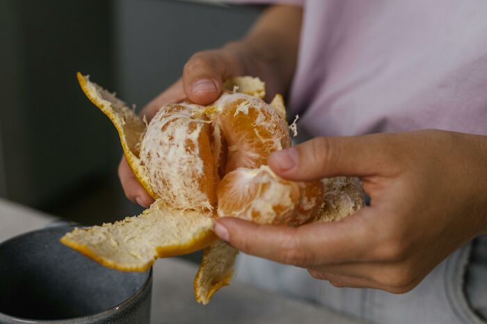 Hands peeling an orange, emphasizing childhood innocence.
